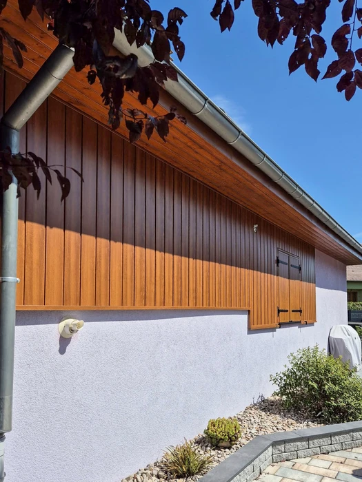Façade extérieure d'un bâtiment résidentiel avec bardage vertical en aluminium laqué imitation bois, teinte chêne doré