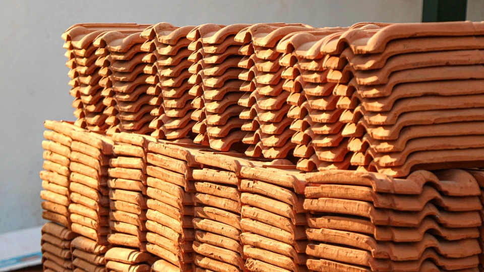 Une photo réaliste montrant un professionnel du bâtiment (artisan couvreur ou zingueur) et un client discutant autour d'un devis posé sur une table de travail, dans le contexte d'un chantier ou d'un bureau, en train d'examiner le document du financement proposé. L'image doit transmettre la confiance, la clarté et le sérieux de la transaction commerciale.