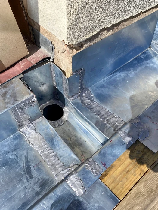 Façade extérieure d'un bâtiment commercial avec installation neuve de gouttière et descente pluviale en zinc prépeiné anthracite (RAL 7016)