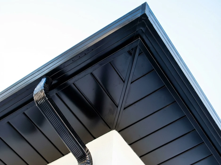 Angle extérieur d'un mur de clôture en béton enduit, recouvert de couvre-murs en aluminium laqué gris argenté