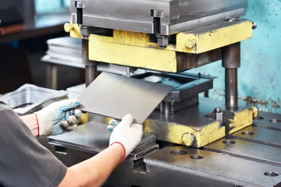 Atelier industriel intérieur avec ouvrier en gants blancs manipulant une presse hydraulique ou machine de découpe